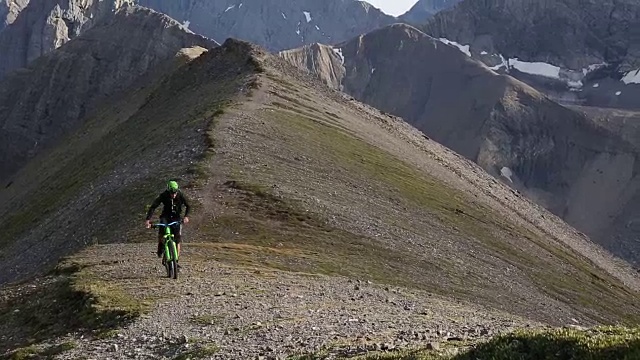 山地自行车穿过高高的山脊，下面是山谷视频素材