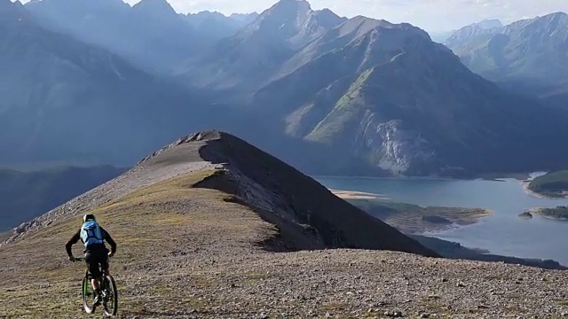 山地自行车穿过高高的山脊，下面是山谷视频素材