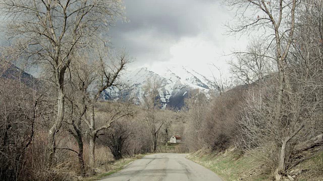 时间流逝从道路上的光秃秃的树木和积雪覆盖的山。视频素材