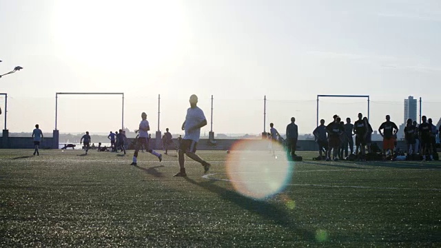 一群年轻人在日落时踢足球——2016年夏天——4k视频素材