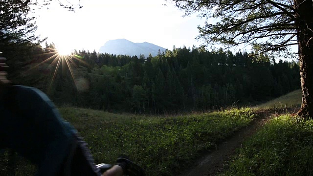 骑山地自行车的人沿着小路穿过草地，望向群山和森林视频素材