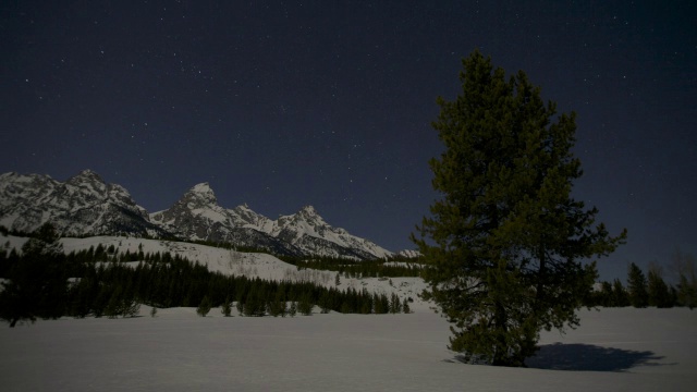 星星在白雪覆盖的树木和山峰上转动。视频素材