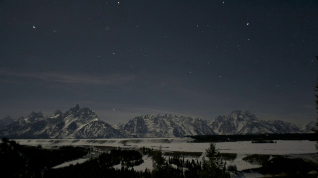 当星星在白雪覆盖的树木和山峰上旋转时，潘离开了。视频素材