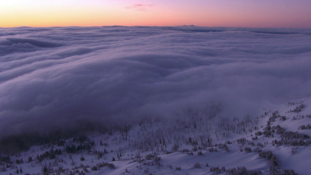 美国黄石公园，日出时，空中航迹在白雪覆盖的山谷和低云之上视频素材