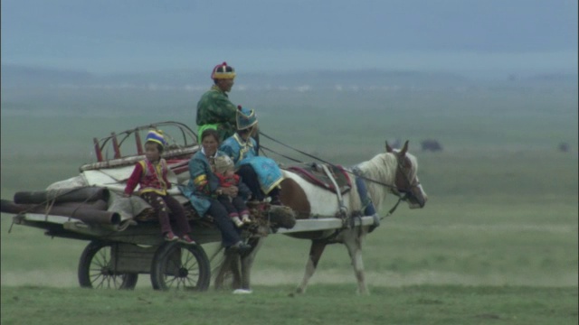 在巴音布鲁克草原上，一家人乘坐载有倒塌蒙古包的马车旅行。视频素材