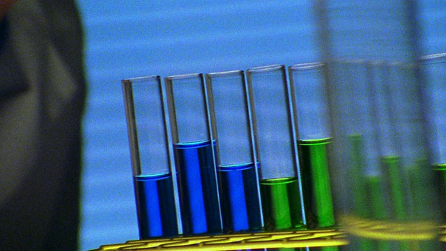 近架聚焦PAN男科学家使用滴管将液体放入装有蓝色液体的试管中视频素材
