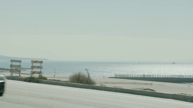 沿海岸道路行驶的汽车的中等角度。海滩和海洋在bg。视频素材