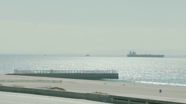 沿海岸道路行驶的汽车的中等角度。海滩和海洋在bg。视频素材