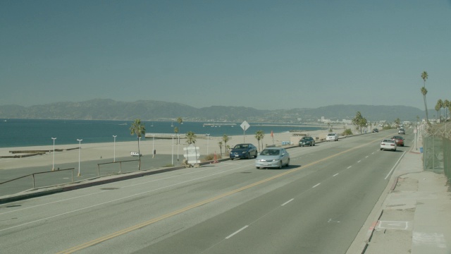 沿海岸道路行驶的汽车的中等角度。海滩和海洋在bg。视频素材