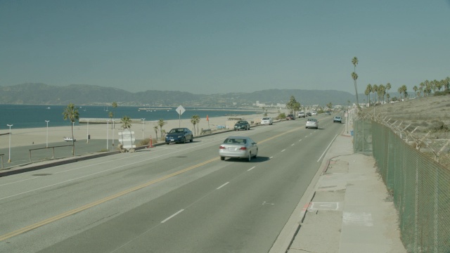 沿海岸道路行驶的汽车的中等角度。海滩和海洋在bg。视频素材