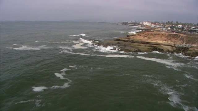 海浪在沿太平洋海岸线的岩石和悬崖上的空中飞行。海洋海滩市政码头。视频素材