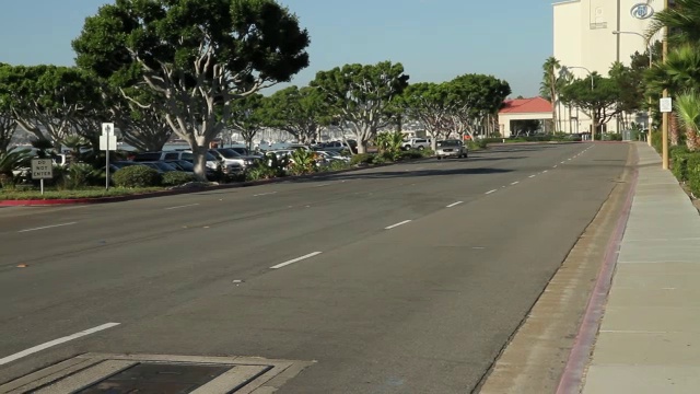 沿滨水区道路行驶的汽车从右向左行驶。圣迭戈城市天际线和海湾在bg。视频素材