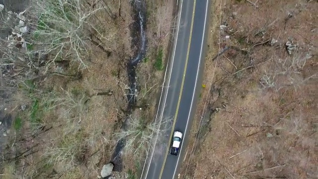 鸟瞰卡车单车道道路，平行于一条岩石河视频素材