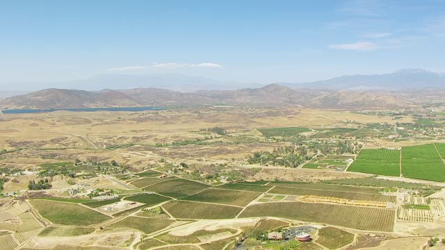 WS AERIAL POV葡萄园和耕地，斯金纳水库和小山的背景，圣伯纳迪诺和圣哈辛托山在朦胧的距离/美国加州的Temecula视频素材