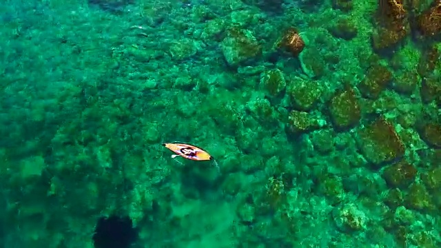 这是一段无人机航拍的画面，两个女孩在夏天的布拉瓦海岸地中海练习皮划艇，那里的海水清澈晶莹，风景如画。4 k UHD。视频素材