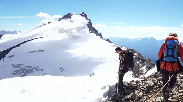 两个年轻的登山运动员走到檐口上，眺望冰川对面的山峰视频素材