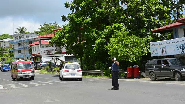 密克罗尼西亚科洛尼亚波纳佩市主要城镇的交通警察在十字路口指挥交通与汽车的行驶视频素材