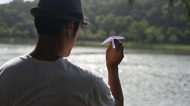 那个人在湖边扔纸飞机。视频素材