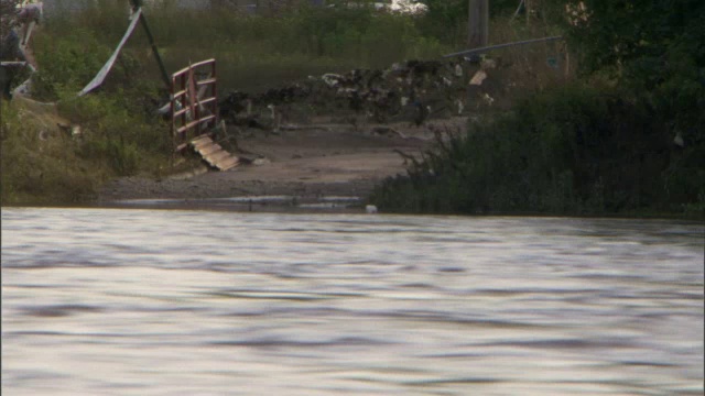 泛滥的河水迅速流过被冲坏的道路。视频素材