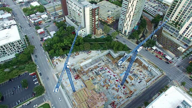 AERIAL:两台蓝色建筑起重机在德克萨斯州奥斯汀的Construction Sight建造下一座摩天大楼共管公寓，从起重机上俯瞰视频素材