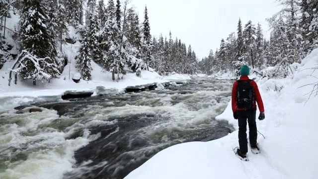 穿着雪地鞋的男性行走者在拉普兰河岸边视频素材