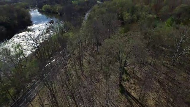 与河流平行的道路鸟瞰图，沿着河岸的树木移动视频素材