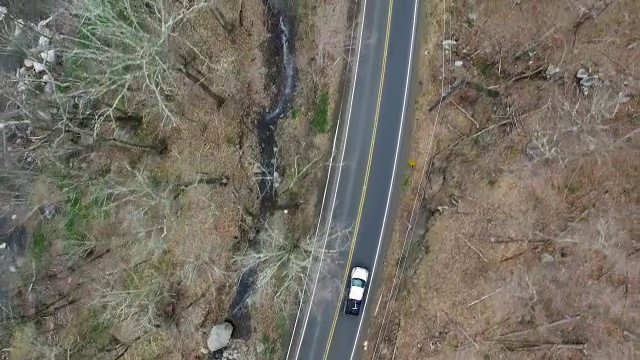 鸟瞰卡车单车道道路，平行于一条岩石河视频素材