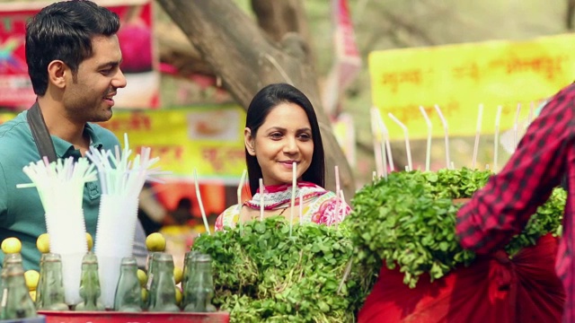 年轻夫妇在摊位喝jal jeera, Suraj Kund Fair，法里达巴德，哈里亚纳邦，印度视频素材