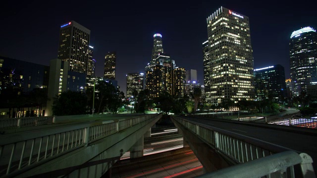 夜间在街道和桥梁上行驶的车辆，背景是现代建筑视频素材