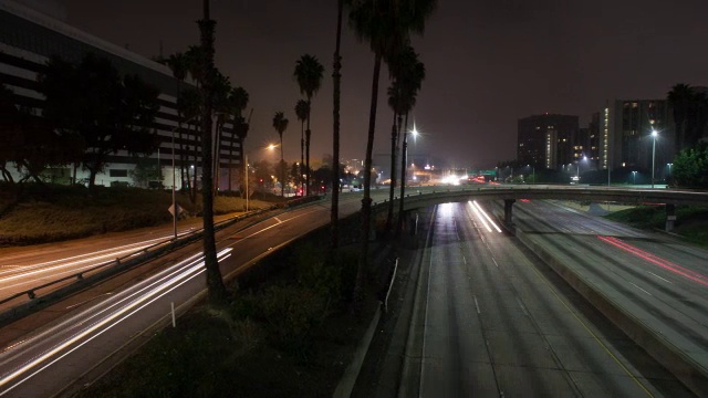 夜间有桥的街道上行驶的车辆，背景是建筑物视频素材