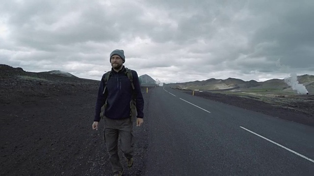 游客背着背包在冰岛荒凉的路上徒步旅行视频素材