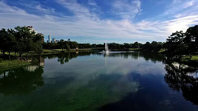 鸟瞰图:湖崖公园近水楼台，晨光映照，喷泉在空中喷溅，背景是达拉斯的德克萨斯天际线视频素材