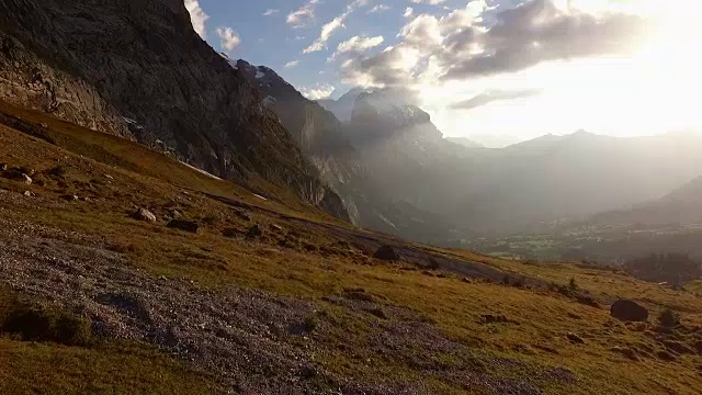 从空中(无人机)拍摄的徒步旅行者在日落时分攀登高山草甸视频素材