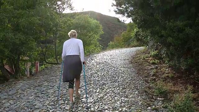 一名女子拄着登山杖，沿着鹅卵石走廊行走视频素材