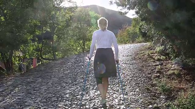 一名女子拄着登山杖，沿着鹅卵石走廊行走视频素材