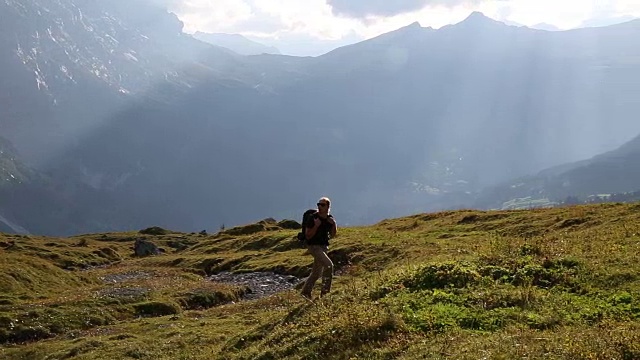 男性徒步旅行者穿越高山草甸，山下视频素材