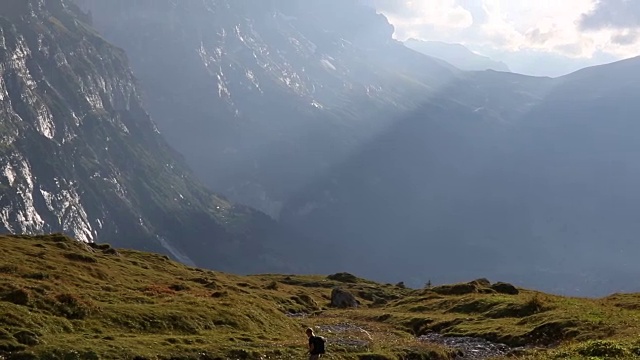 男性徒步旅行者穿越高山草甸，山下视频素材