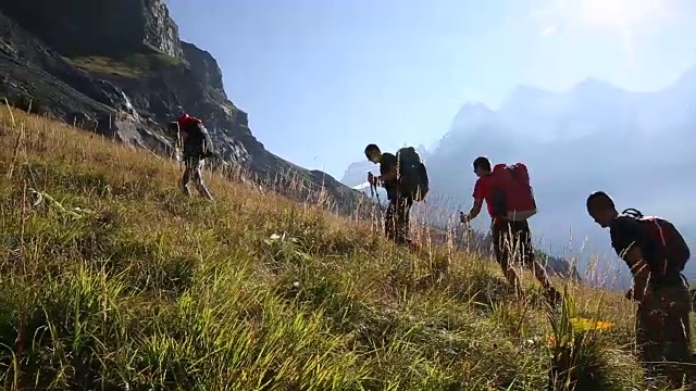 一群徒步旅行者爬上湖面上陡峭的山坡视频素材