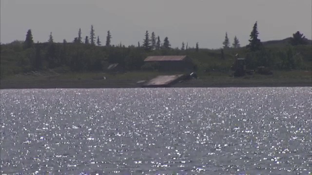 宽阔的镜头，波光粼粼的湖与农场建筑的背景视频素材