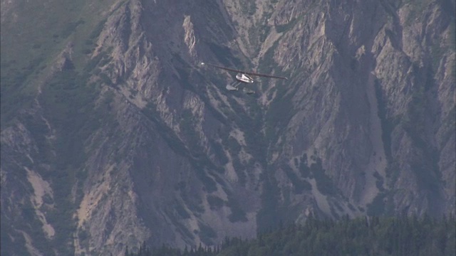 宽阔的镜头水上飞机飞行与大山脉和森林的背景视频素材