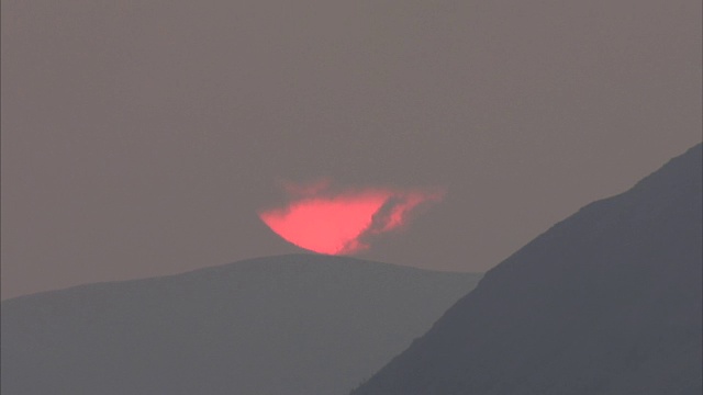 大红色的太阳被云覆盖在山上的广角镜头视频素材