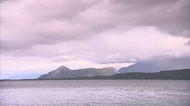 宽阔的湖泊与森林和群山被云包围的背景视频素材