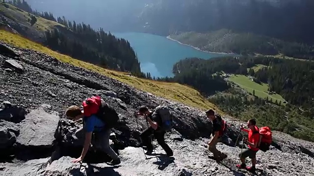 一群徒步旅行者爬上湖面上陡峭的山坡视频素材