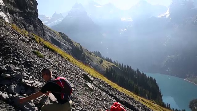 一群徒步旅行者爬上湖面上陡峭的山坡视频素材