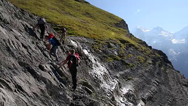 一群徒步旅行者爬上湖面上陡峭的山坡视频素材