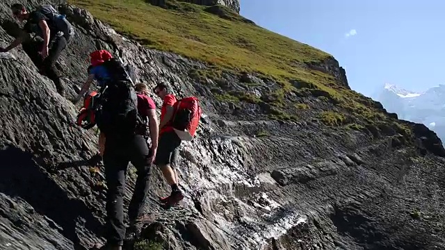 一群徒步旅行者爬上湖面上陡峭的山坡视频素材