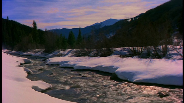 宽拍摄流在雪与落基山脉的背景/特柳赖德附近，科罗拉多州视频素材