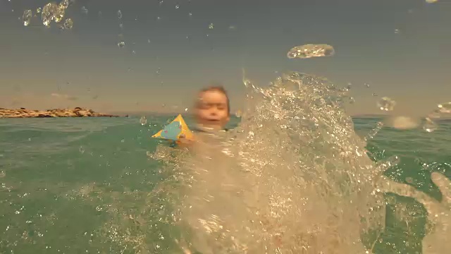 小女孩在海里游泳，溅水花。视频素材