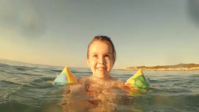 小女孩在海里游泳，溅水花。视频素材