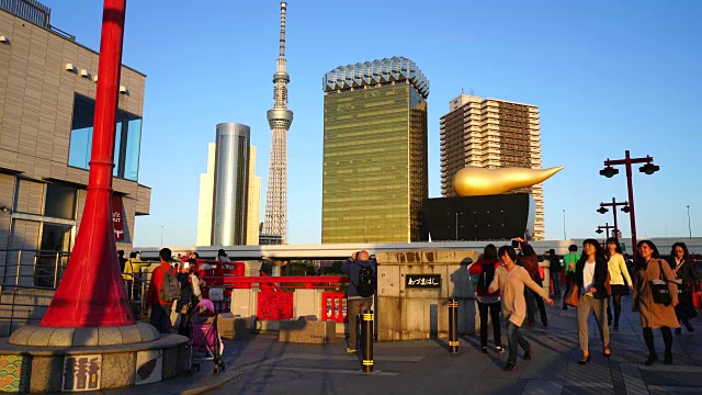 在东京浅草区安桥上，镜头捕捉到了夜间通勤者的身影。夕阳照亮了通勤者、东京天空树和市中心的城市景观。视频素材